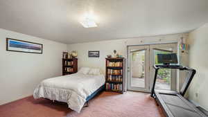 Basement bedroom with walkout to exterior, carpet floors, and a textured ceiling
