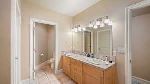 Basement bathroom with double vanity and light tile patterned flooring