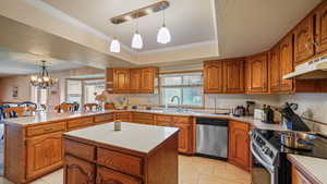 Kitchen with stainless steel appliances, wood finish cabinets, light countertops, a peninsula, and crown molding