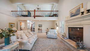 Living area featuring a fireplace with raised hearth, carpet flooring, and a ceiling fan