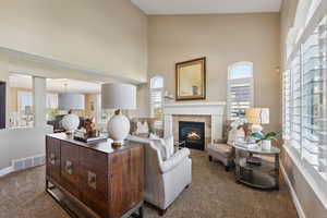 Living room with dark colored carpet, a high ceiling, and a tile fireplace