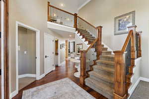 Entryway featuring dark wood finished floors, a high ceiling, recessed lighting, and crown molding