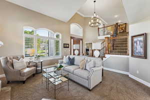 Living room featuring carpet floors, suspended lighting, crown molding, and lofted ceiling
