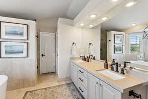 Full bath featuring a freestanding bath, a shower stall, double vanity, recessed lighting, and light tile patterned floors
