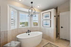 Bathroom with a soaking tub, tile walls, a shower stall, and a wainscoted wall