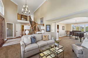 Living room featuring crown molding, suspended lighting, a high ceiling, and arched walkways