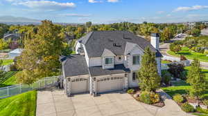 View of front of house featuring concrete driveway, stucco siding, a garage, stone siding, and a chimney