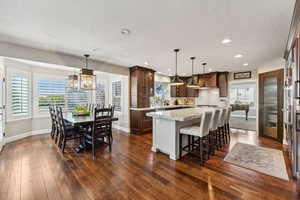 Kitchen with a kitchen island, a breakfast bar area, dark wood-style floors, hanging light fixtures, and dark wood finish cabinetry