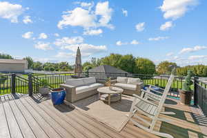 Deck featuring an outdoor living space, a lawn, and view of wooded area