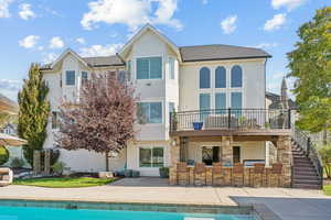 Back of house with stucco siding, an outdoor pool, stone siding, and a patio