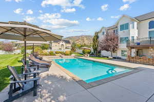 View of pool with patio surround, a mountain view, a fenced backyard, and exterior bar