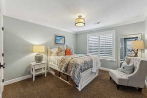Bedroom with crown molding and dark carpet