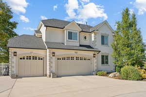 Traditional home with driveway, stucco siding, roof with shingles, an attached garage, and stone siding