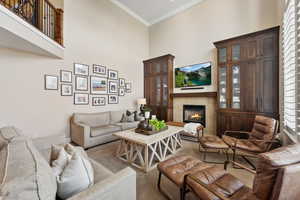 Living area featuring a high ceiling, a fireplace, ornamental molding, and carpet floors