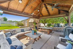View of patio with an outdoor stone fireplace, area for grilling, outdoor lounge area, and a ceiling fan