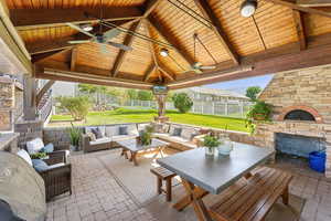 Fenced backyard with an outdoor living space with a fireplace, a ceiling fan, and a patio