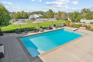 View of pool with a fenced backyard, patio surround, and a diving board