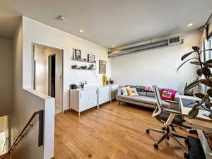 Office featuring light wood finished floors, recessed lighting, and bar area