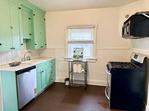 Kitchen featuring stainless steel appliances, green cabinets, dark wood-type flooring, and decorative backsplash