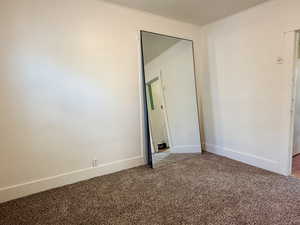Unfurnished bedroom with carpet flooring and baseboards