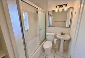 Bathroom with light tile patterned floors and shower / bath combination with glass door