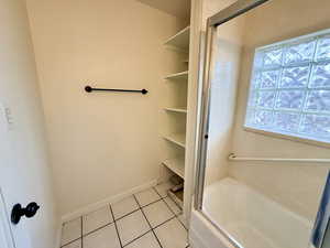 Full bathroom featuring light tile patterned floors, a tub to relax in, and a closet