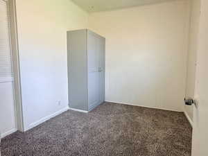 Unfurnished bedroom with dark colored carpet and ornamental molding