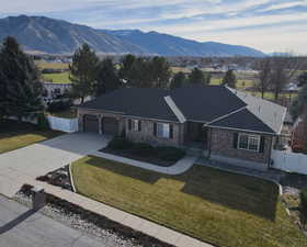 Ranch-style house featuring driveway, an attached garage, a mountain view, brick siding, and a shingled roof