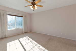 Carpeted empty room featuring baseboards and a ceiling fan