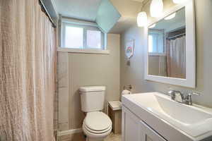 Full bathroom featuring vanity, curtained shower, healthy amount of natural light, and a textured ceiling