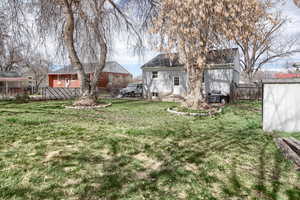 Rear view of house with a fenced backyard, a storage unit, and entry steps