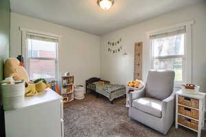 Bedroom featuring dark colored carpet, multiple windows, and a textured ceiling