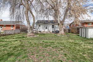 Back of property featuring a fenced backyard and a storage unit