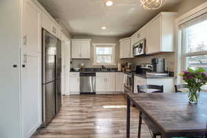 Kitchen featuring stainless steel appliances, light wood-type flooring, white cabinetry, and recessed lighting