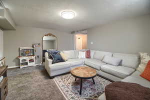 Carpeted living room featuring a textured ceiling and baseboards