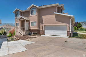 View of front of home featuring stucco siding, brick siding, and concrete driveway