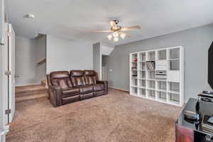Carpeted living room with stairs and ceiling fan