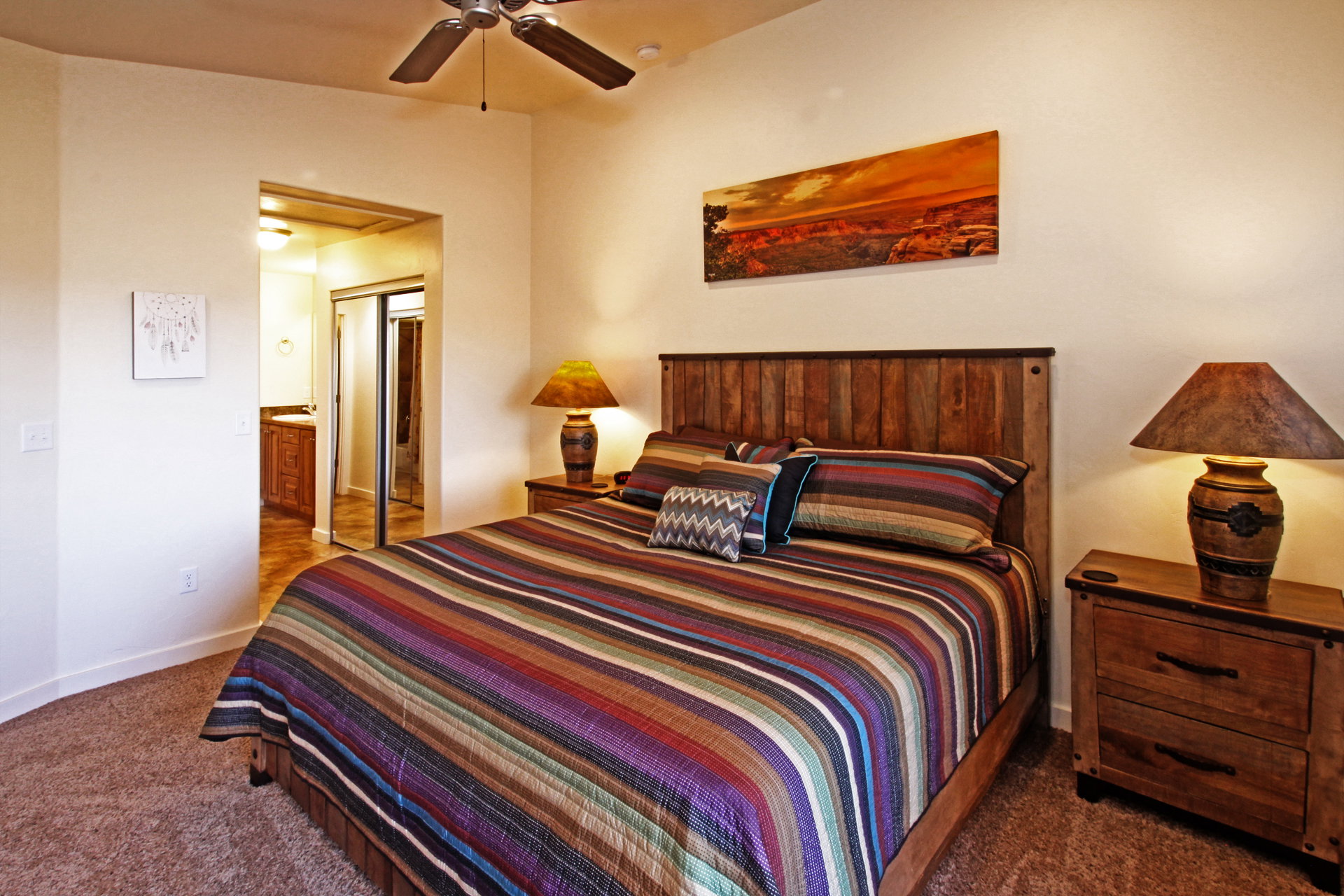 Bedroom featuring dark colored carpet, ensuite bathroom, ceiling fan, and a closet