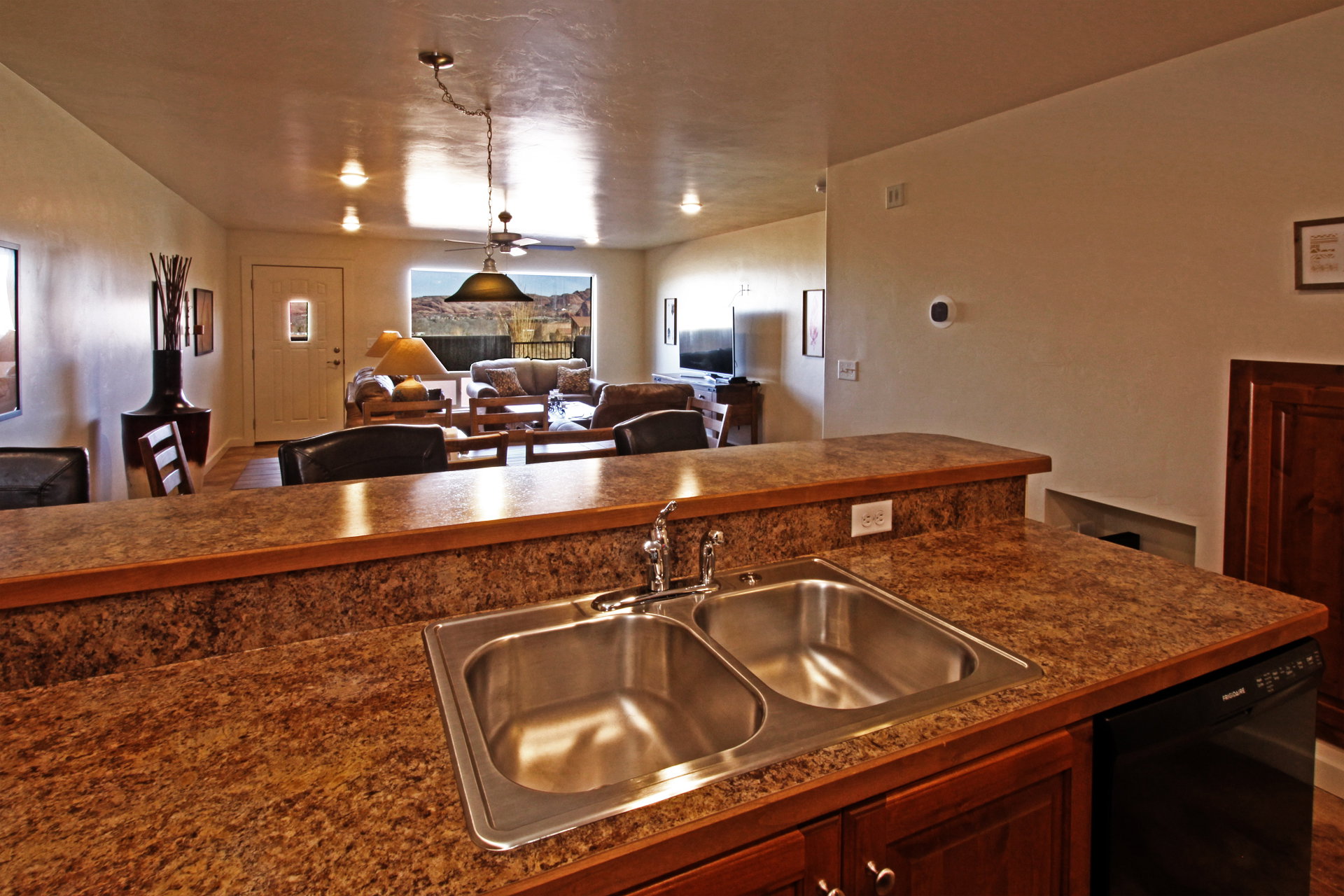Kitchen featuring dark countertops, open floor plan, black dishwasher, and a ceiling fan