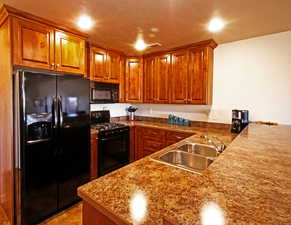 Kitchen featuring wood finish cabinets, black appliances, and a peninsula