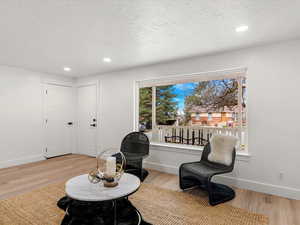 Living area with light wood-style floors, recessed lighting, and a textured ceiling