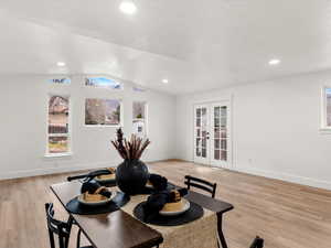 Dining space with french doors, light wood-style floors, lofted ceiling, plenty of natural light, and recessed lighting