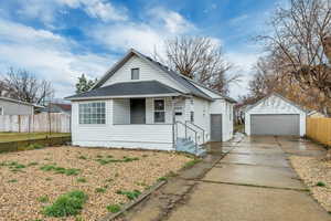 View of front of house featuring an outdoor structure, a garage, roof with shingles, and covered porch