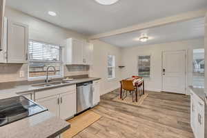 Kitchen featuring dishwasher, white cabinetry, decorative backsplash, light wood-style floors, and black range with electric stovetop