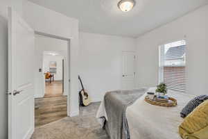 Carpeted bedroom featuring baseboards and a textured ceiling