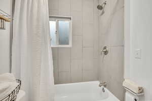 Bathroom featuring shower / bathtub combination with curtain and toilet