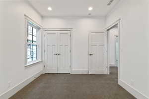 Unfurnished bedroom featuring dark colored carpet, a closet, and recessed lighting