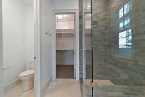 Bathroom featuring a shower stall and a walk in closet