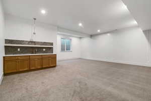 Finished below grade area with light colored carpet and recessed lighting
