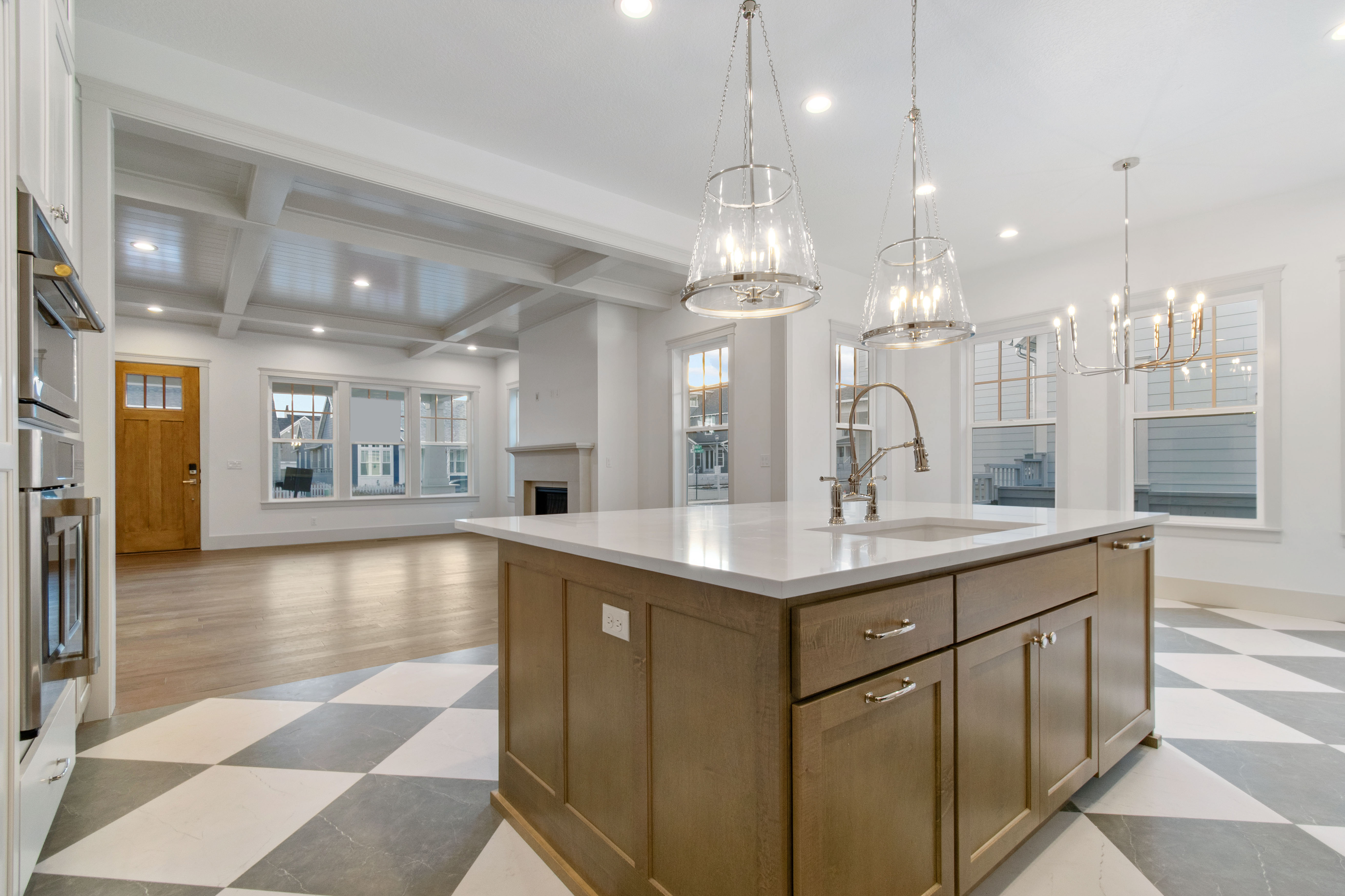 Kitchen featuring open floor plan, a center island with sink, a fireplace, light stone countertops, and stainless steel double oven
